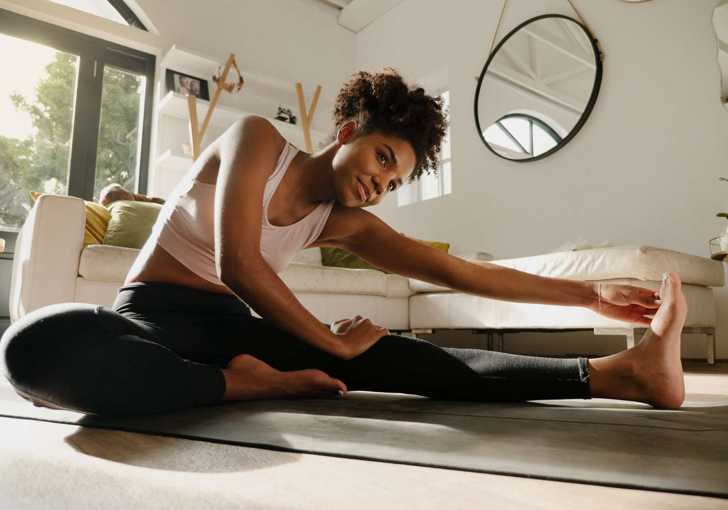 Woman exercising at home, stretching legs and warming up