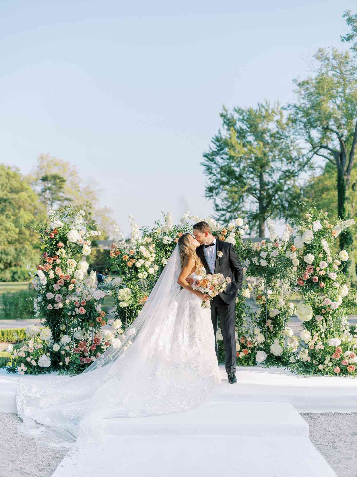 bride and groom kissing in front of floral decor