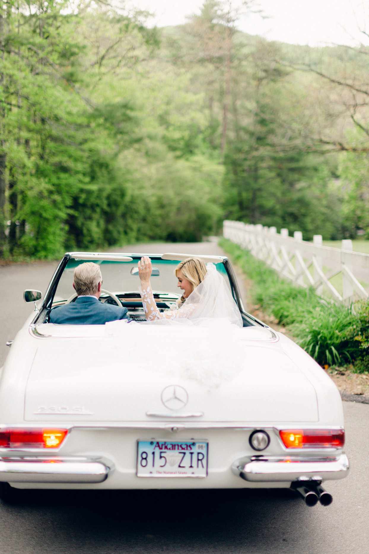 couple driving away in white mercedes convertible