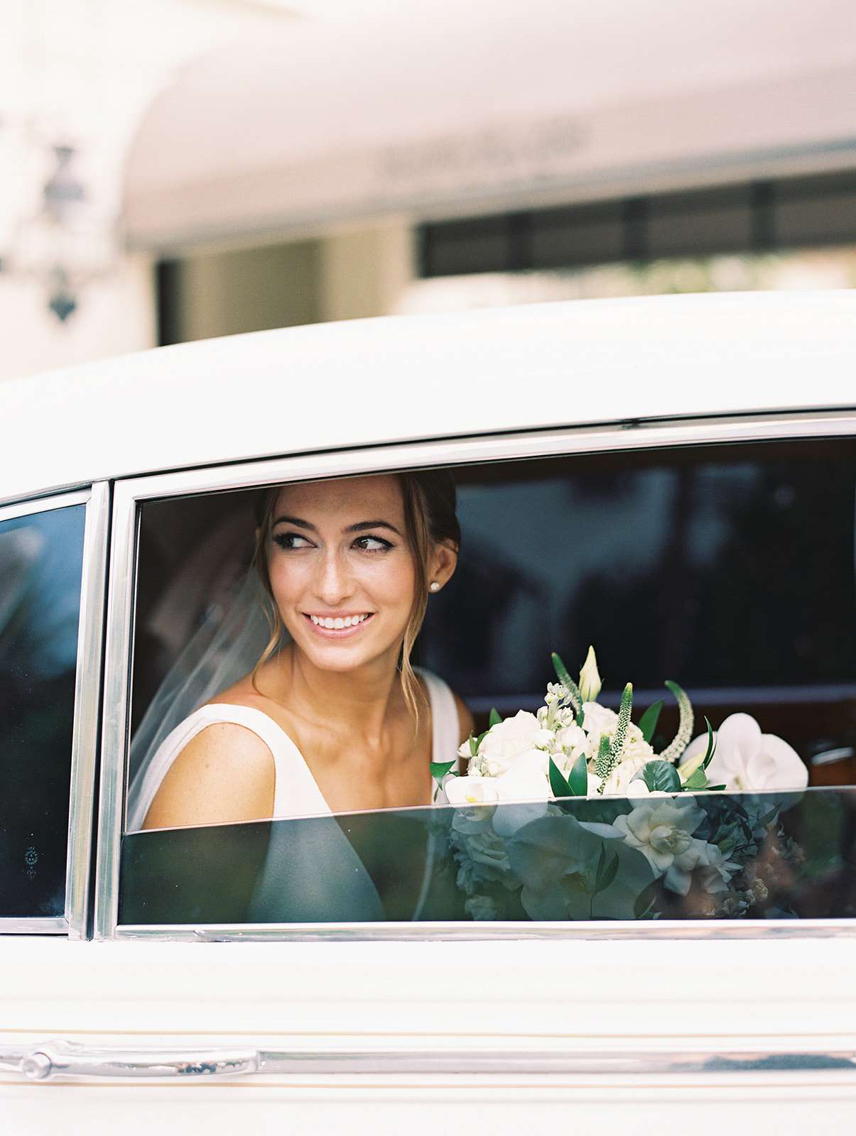 bride looking out the window of car with bouquet