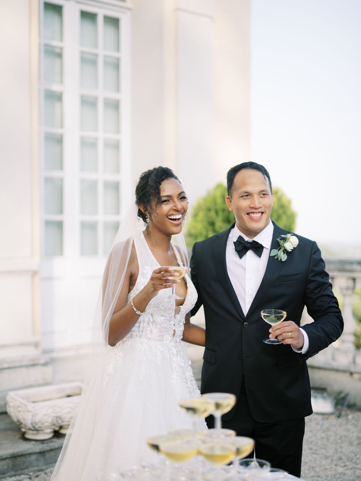 bride and groom smiling holding champagne coupe glasses