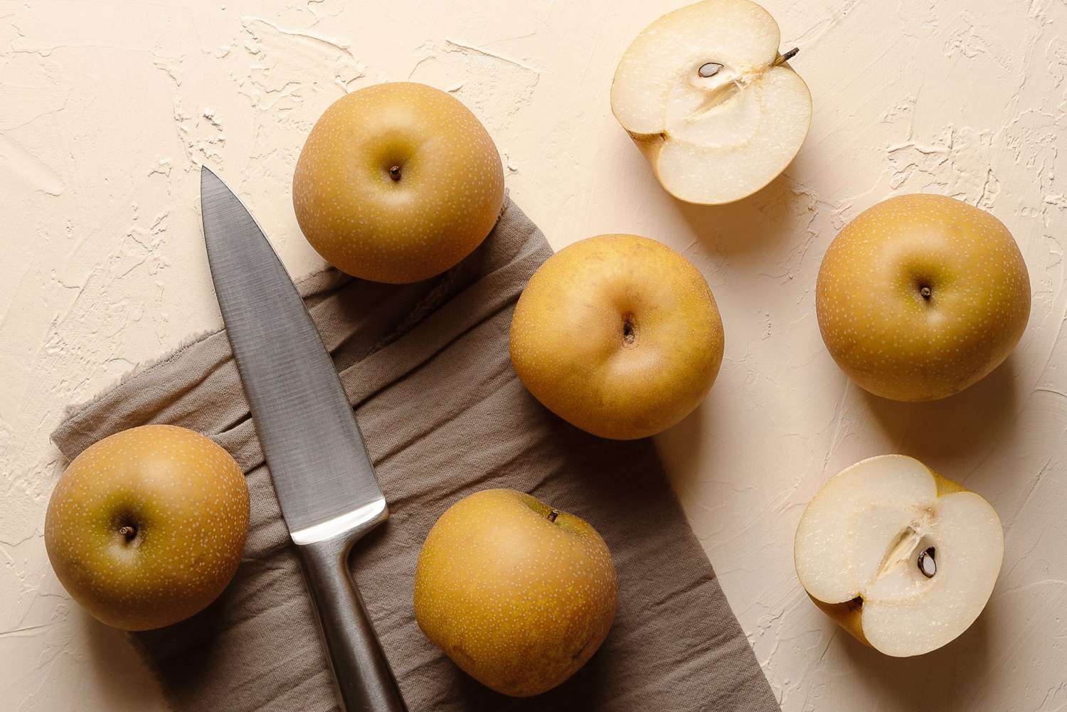 sian pears with a silver knife on a brown piece of cloth