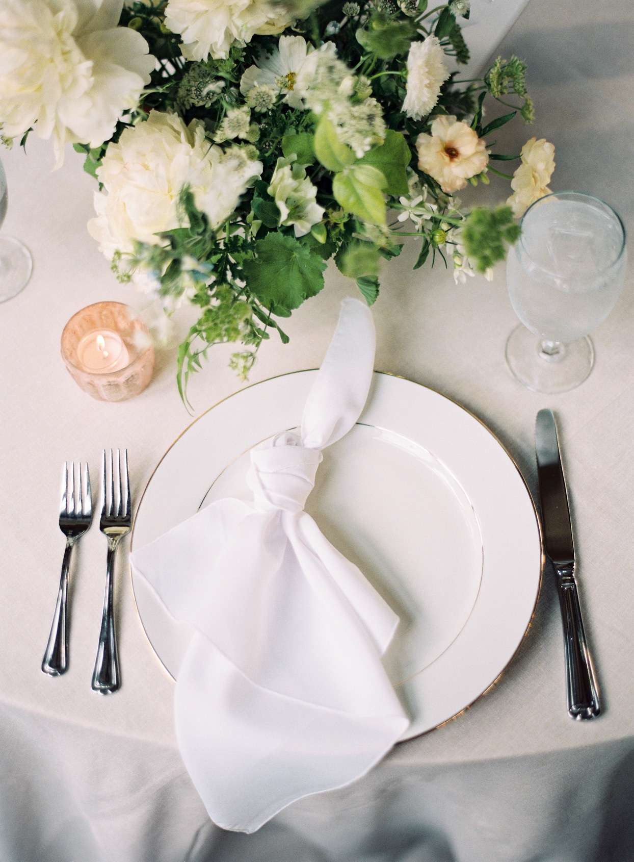 dinner place setting with white napkin and flowers