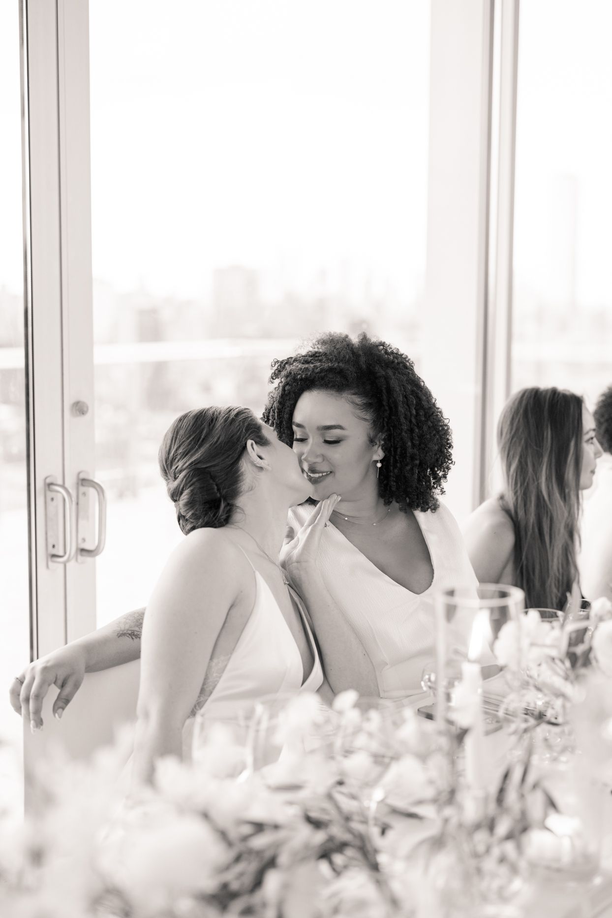 brides kissing at wedding reception table