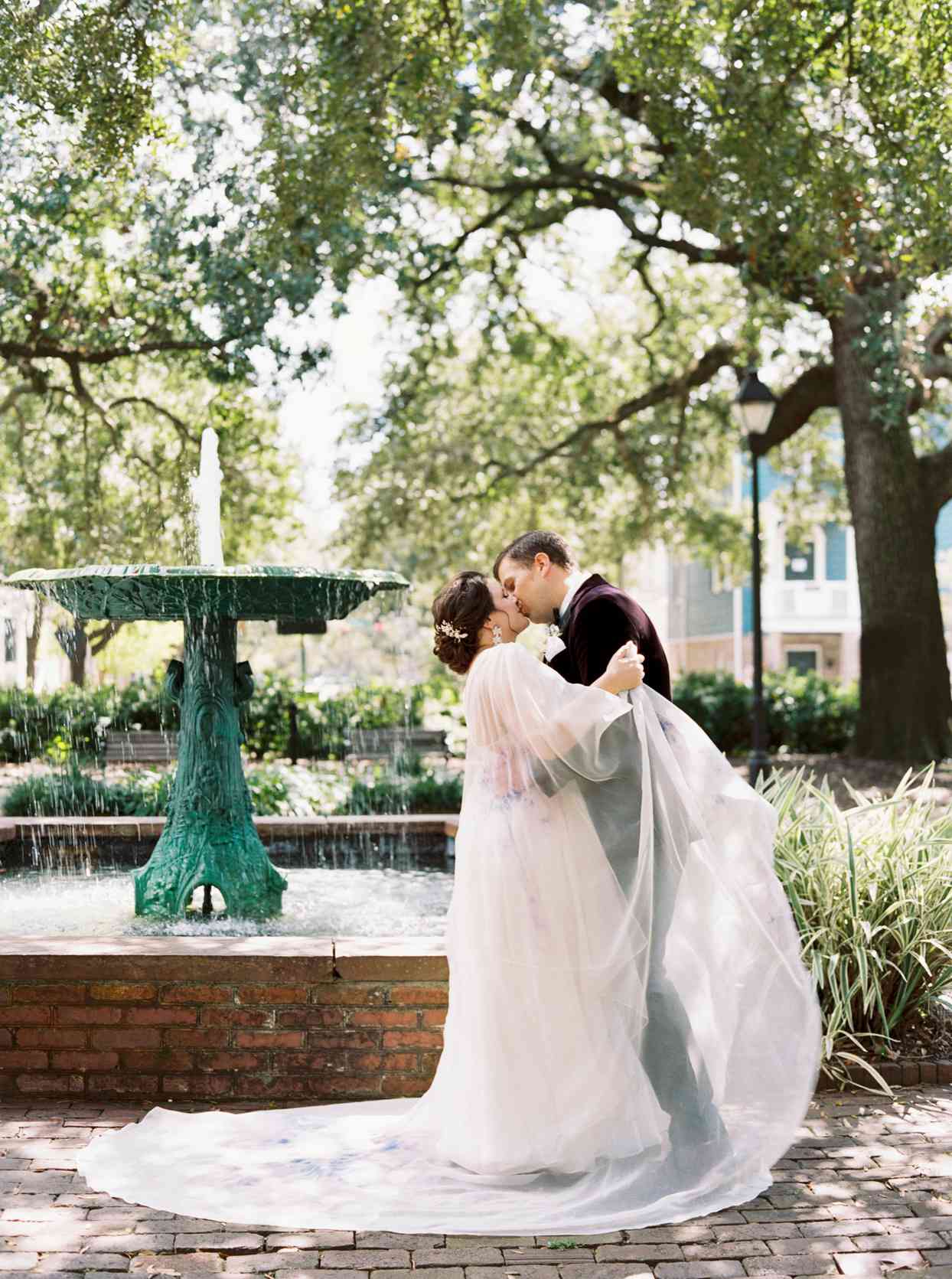 bride and groom kissing by fountain