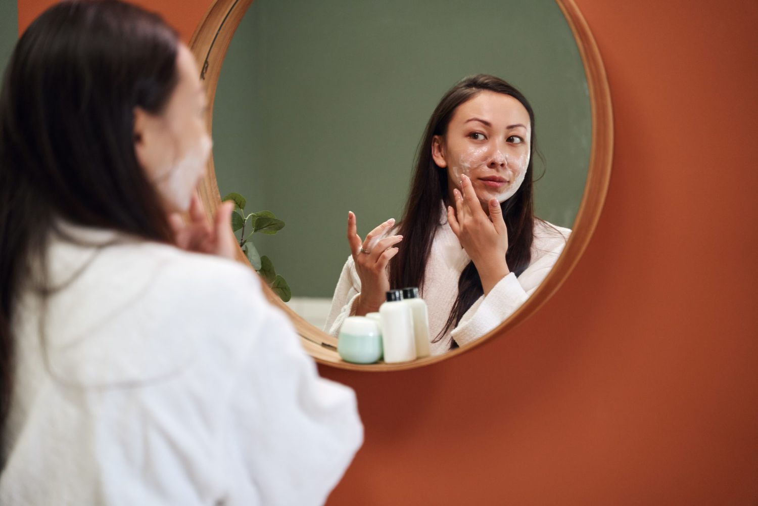 woman applying skincare routine in mirror