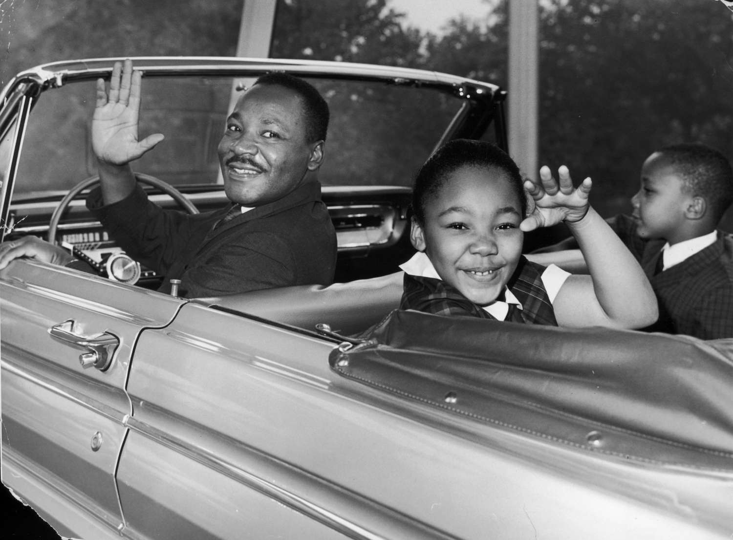 Dr. Martin Luther King Jr. waves with his children, Yolanda and Martin Luther III, from the 'Magic Skyway' ride at the Worlds Fair