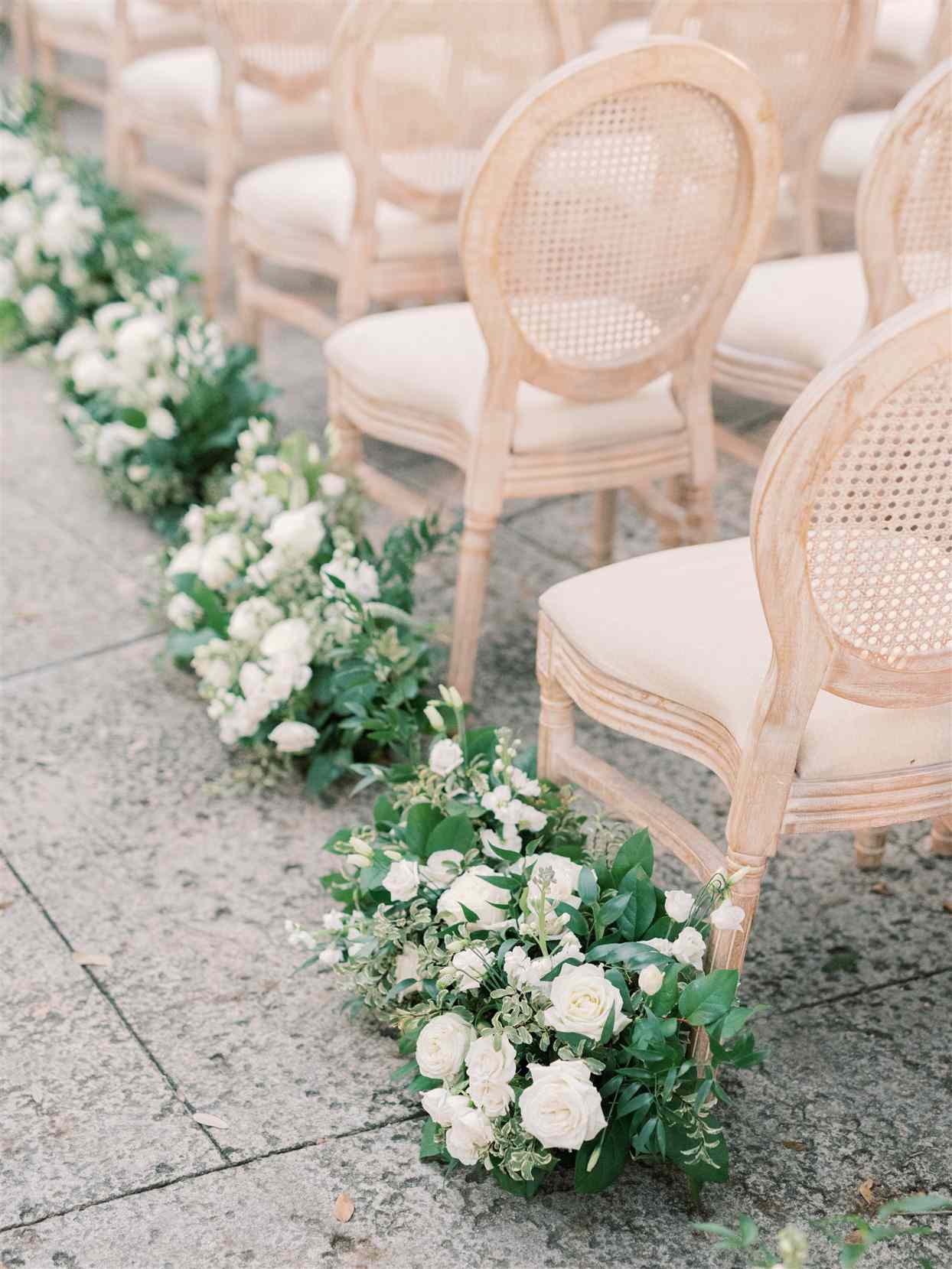 wedding ceremony aisles lined with greenery and white roses