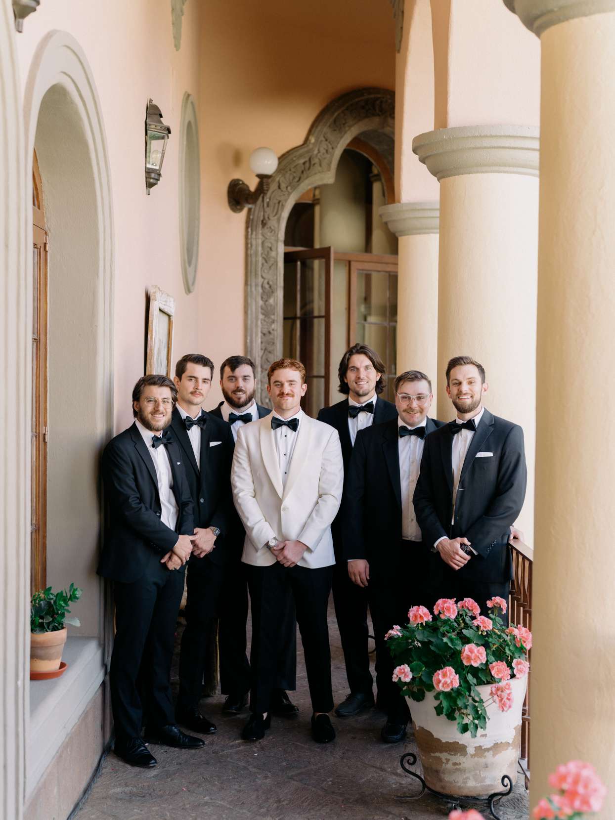 groom wearing white and black suit with six groomsmen