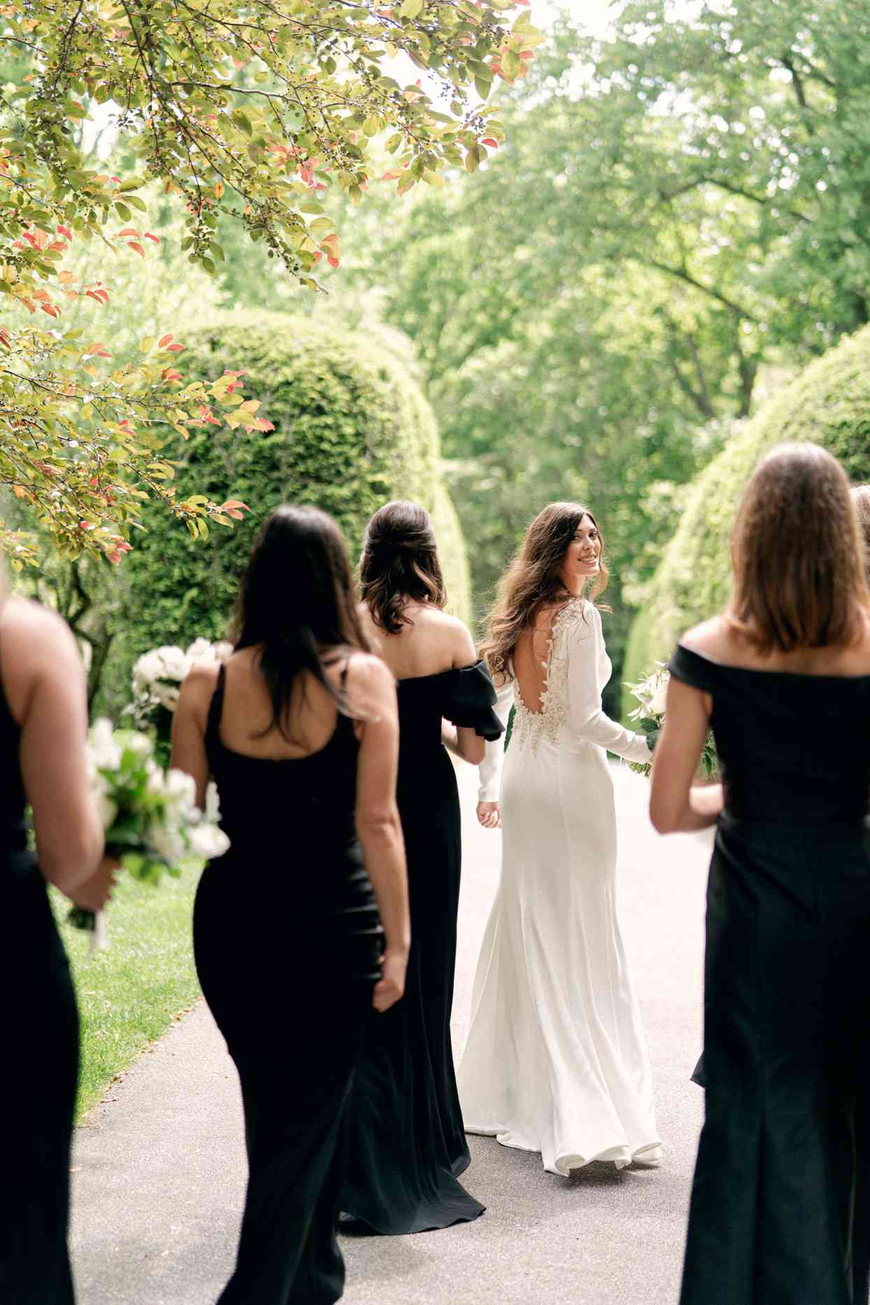 bride smiling with bridesmaids wearing black dresses