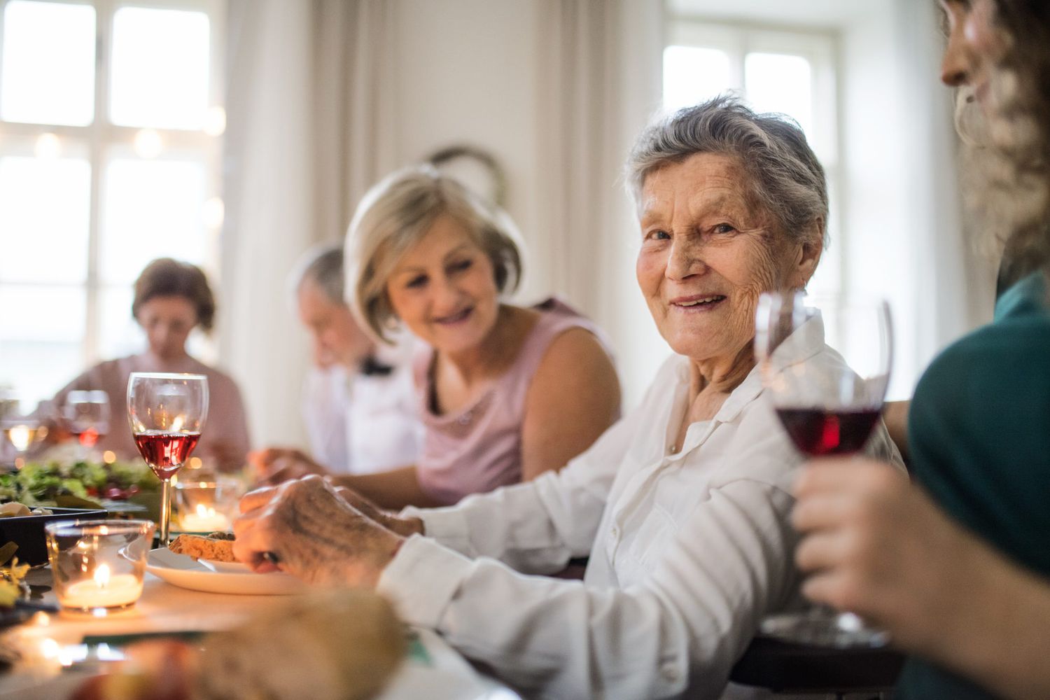 senior woman at dinner table surrounded by family