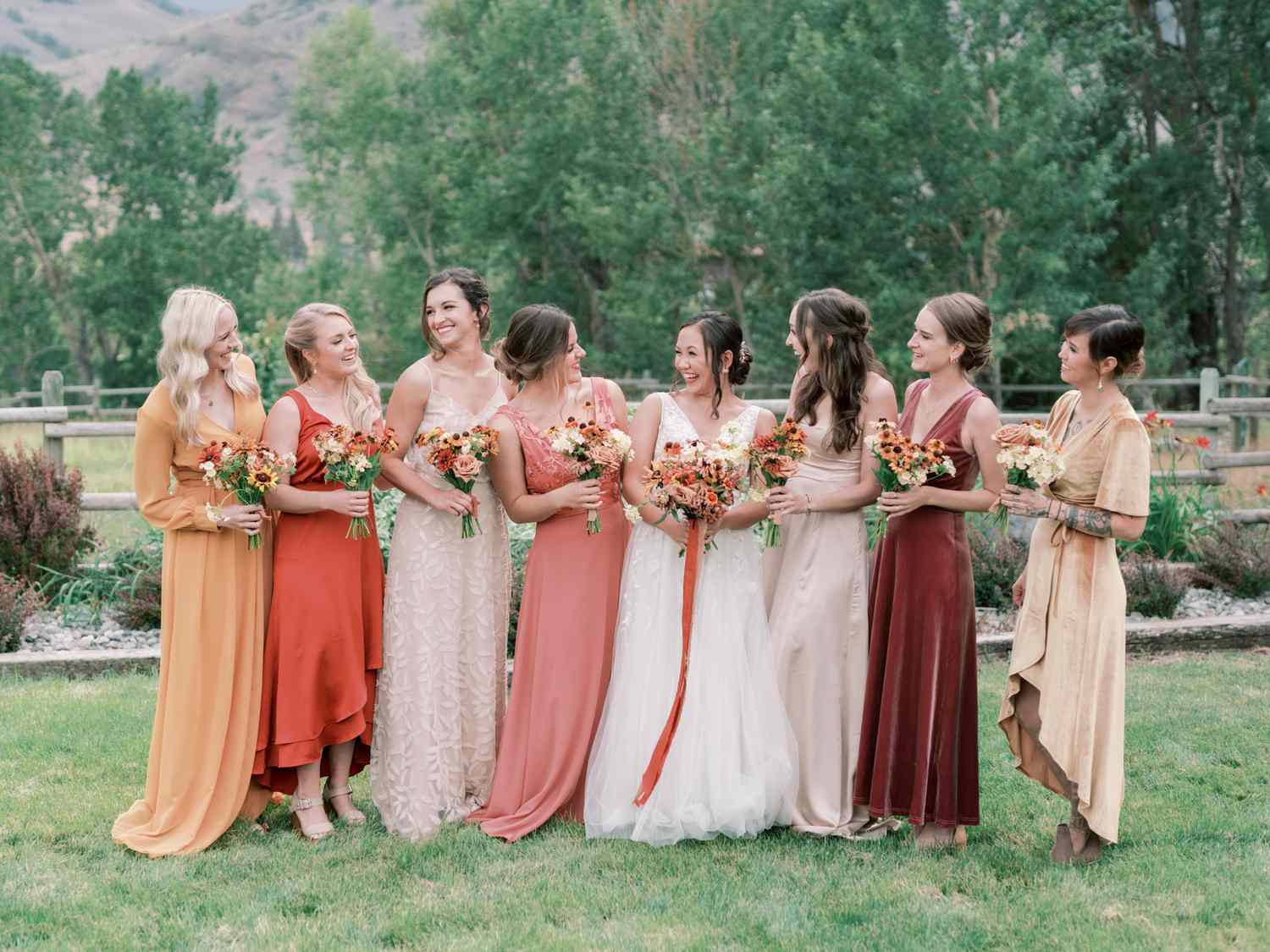 bride with bridesmaids wearing various warm hued dresses with different silhouettes