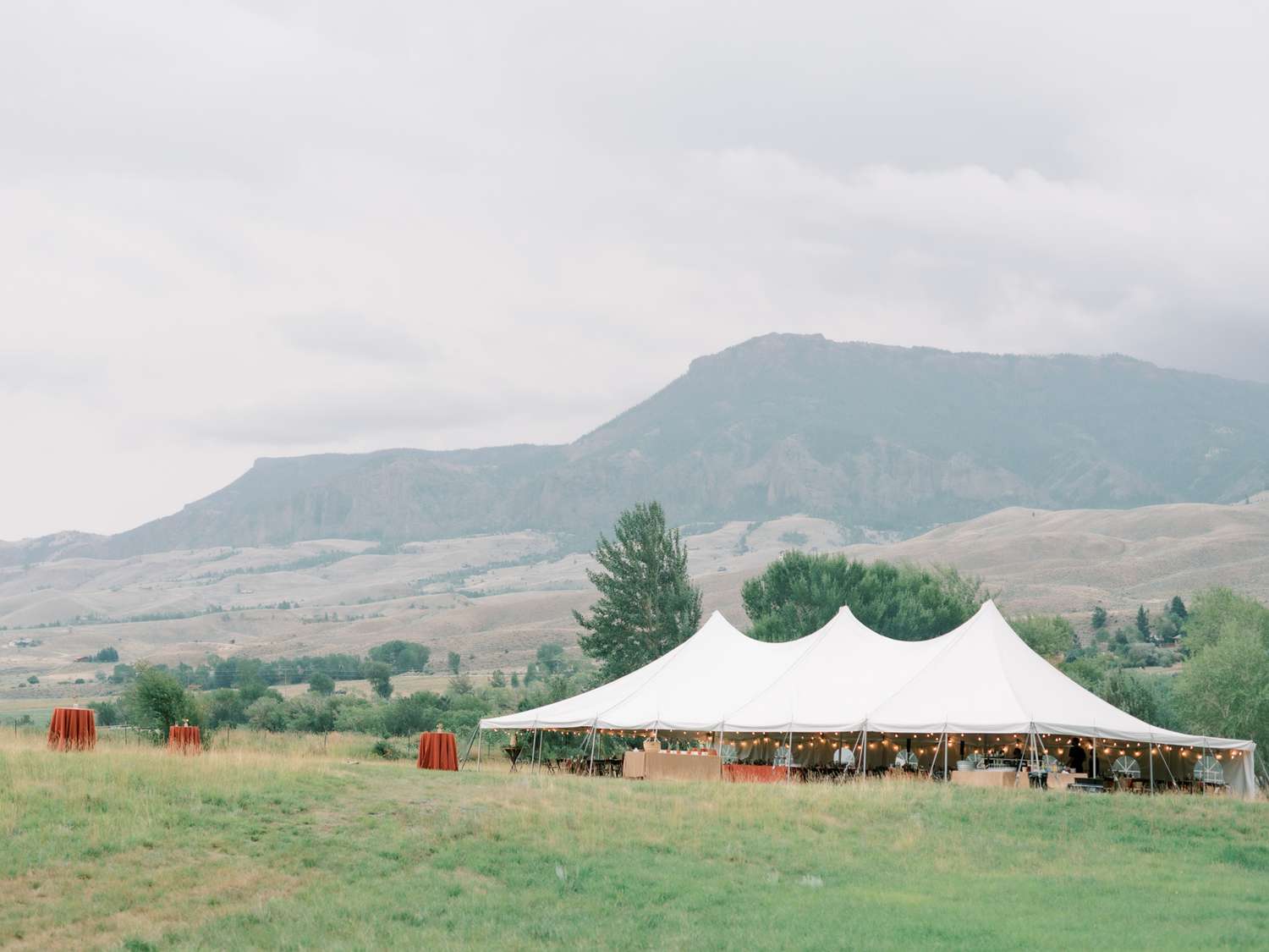 outdoor wedding tent in grassy field overlooking mountains