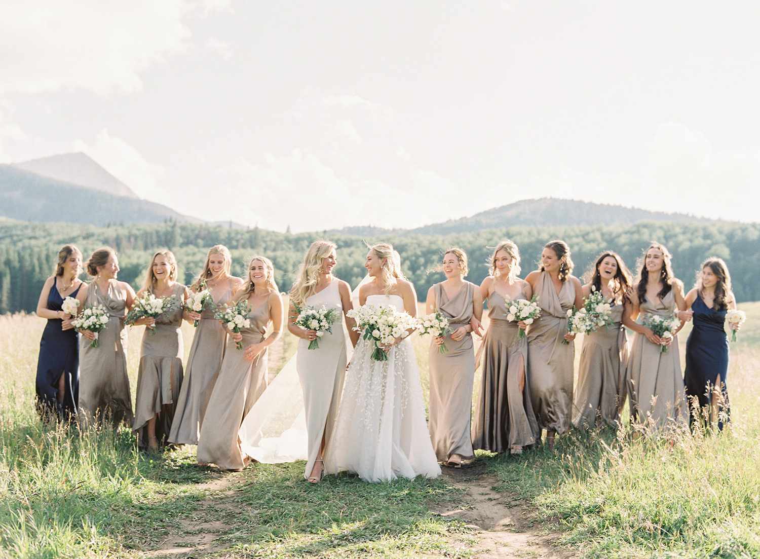 bride walking with large bridal party wearing beige bridesmaids dresses