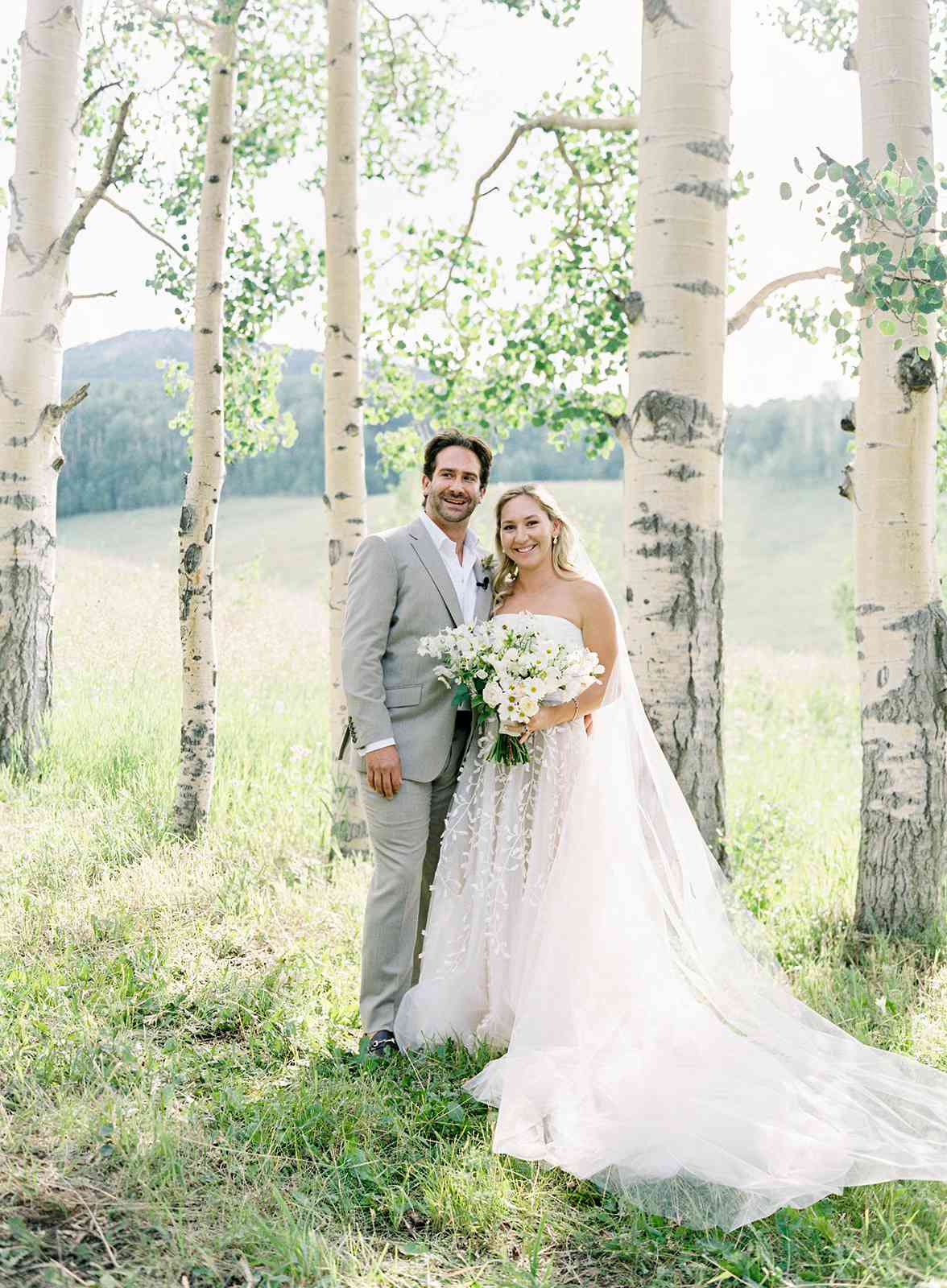 bride and groom smiling outside in wooded area