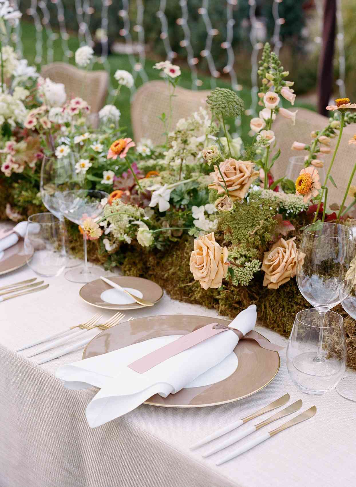 orange toned florals on wedding reception table garland