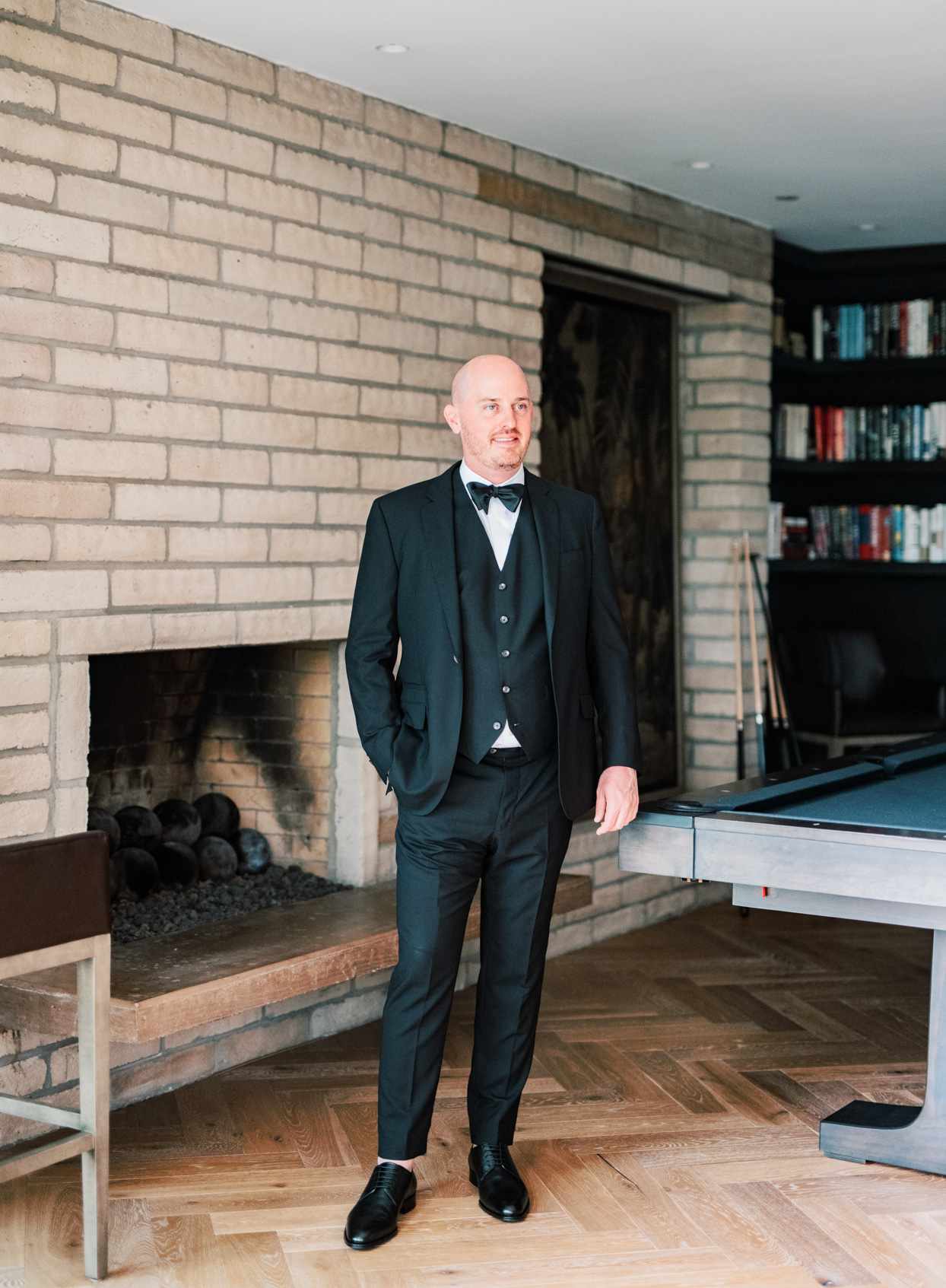 groom in black suit and vest standing indoors