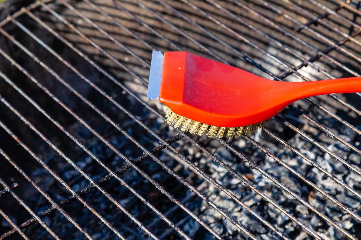 cleaning bbq grill with red wire brush