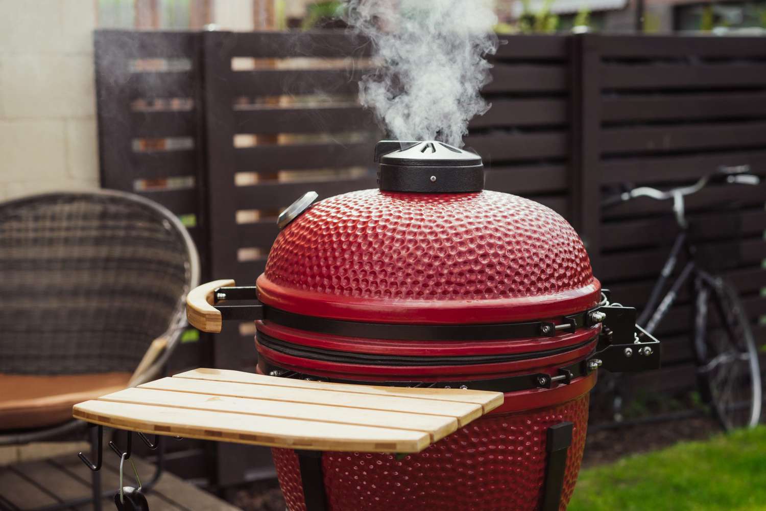 Red Ceramic Barbecue Grill. Grilling, Smoking, Baking, BBQ and Roasting process. Bicycle in the backstage of summer terrace. Lifestyle concept.
