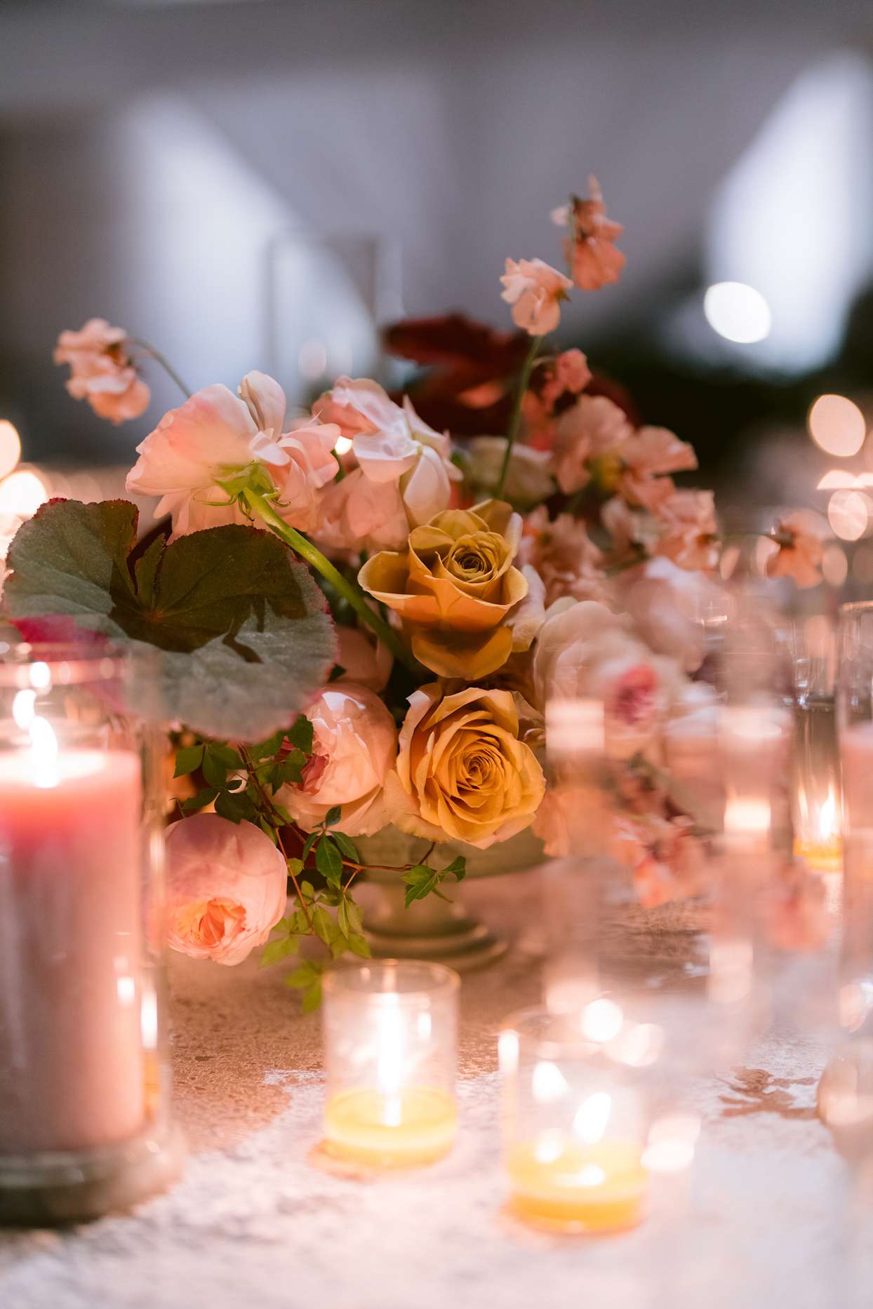 table centerpiece with pink and yellow roses with candles