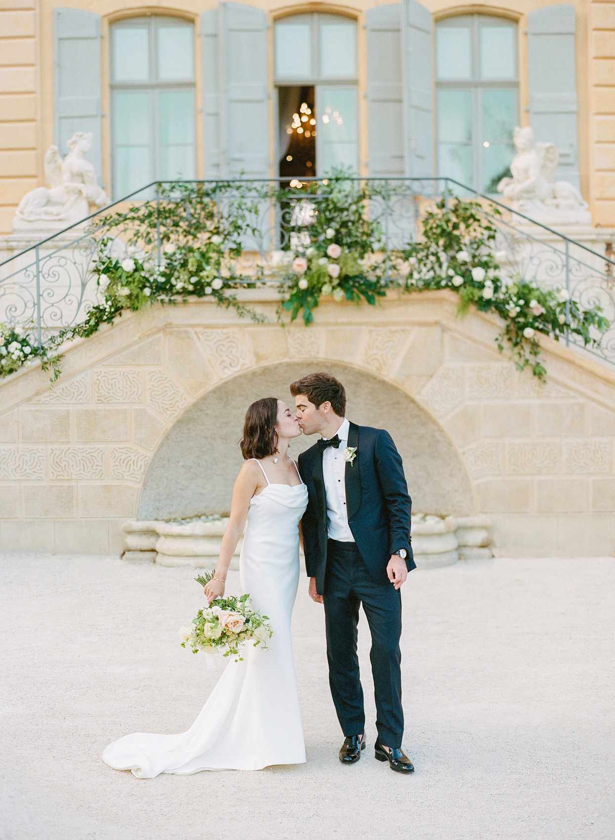 bride and groom kissing in front of french chateau