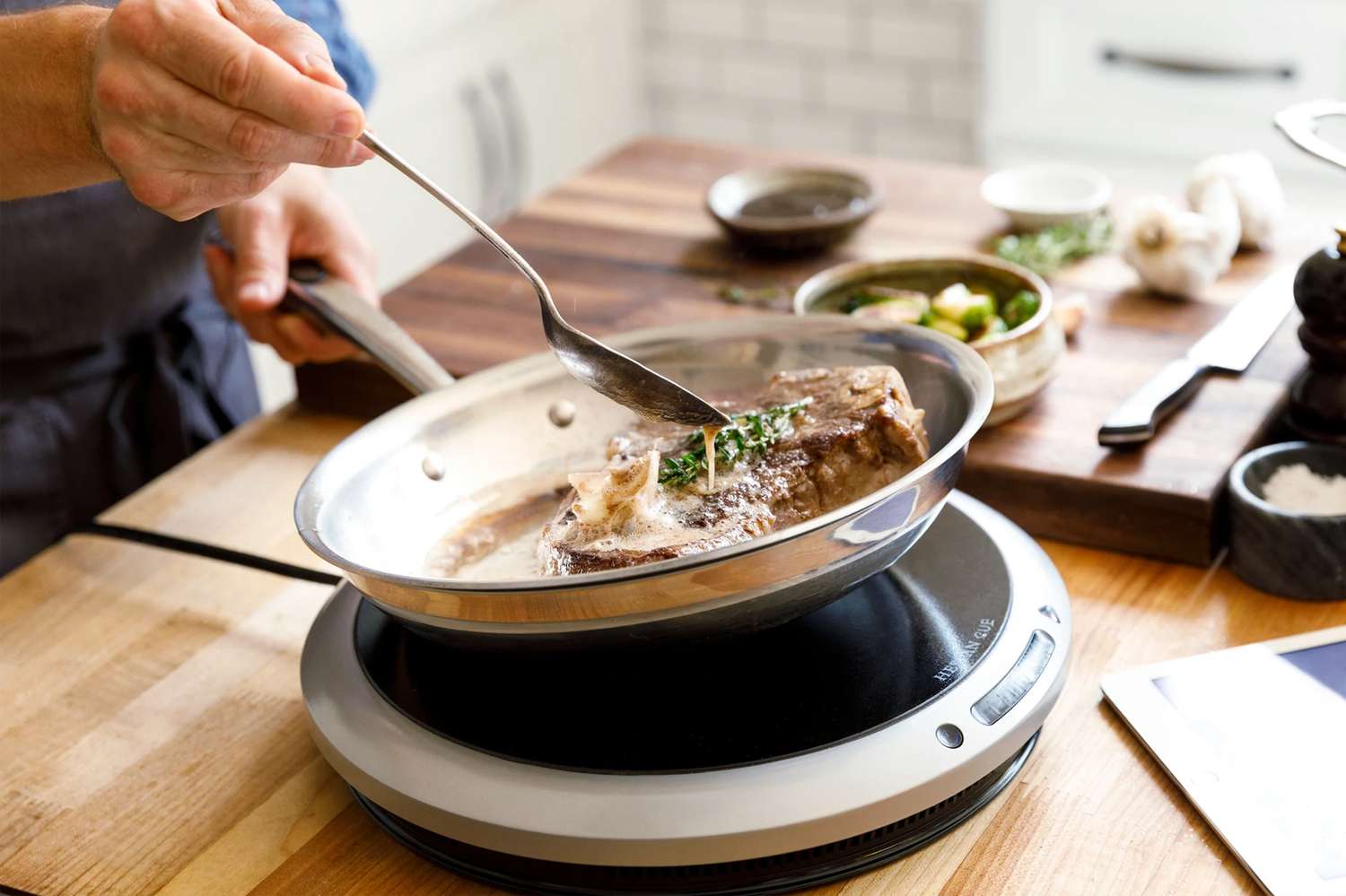 Person cooking over a portable induction cooktop