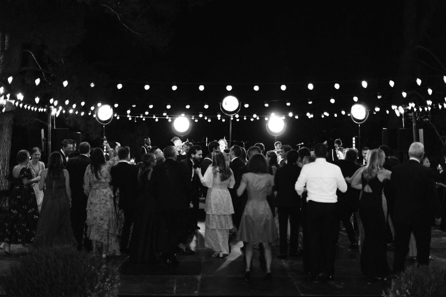 guests dancing during wedding reception under outdoor string lights