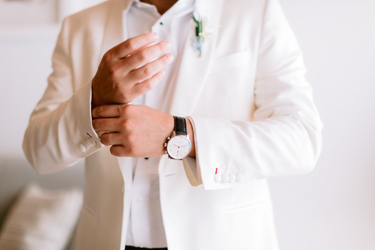 groom wearing white tux and watch