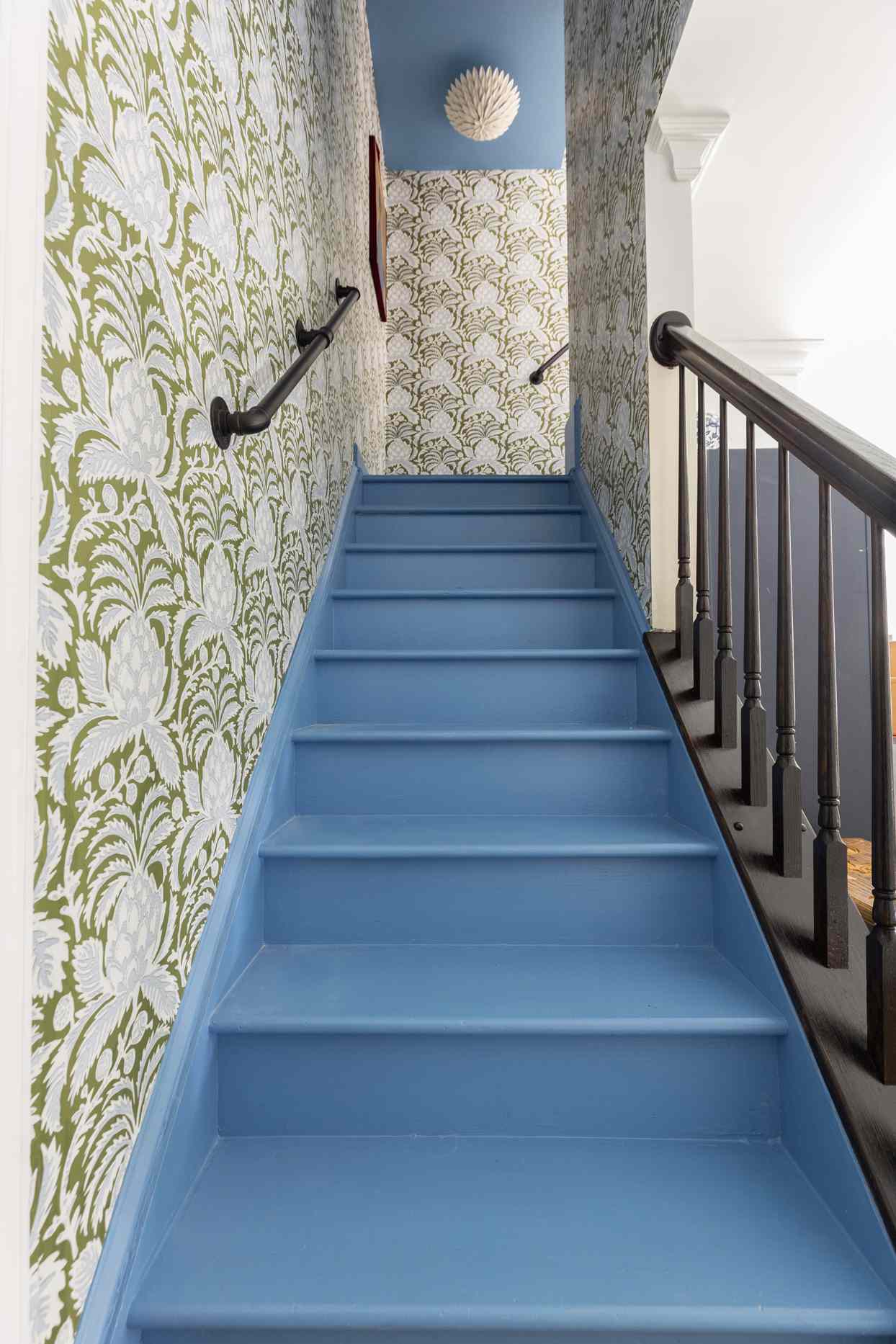 basement with green whimsical wallpaper and cooks blue painted stairs