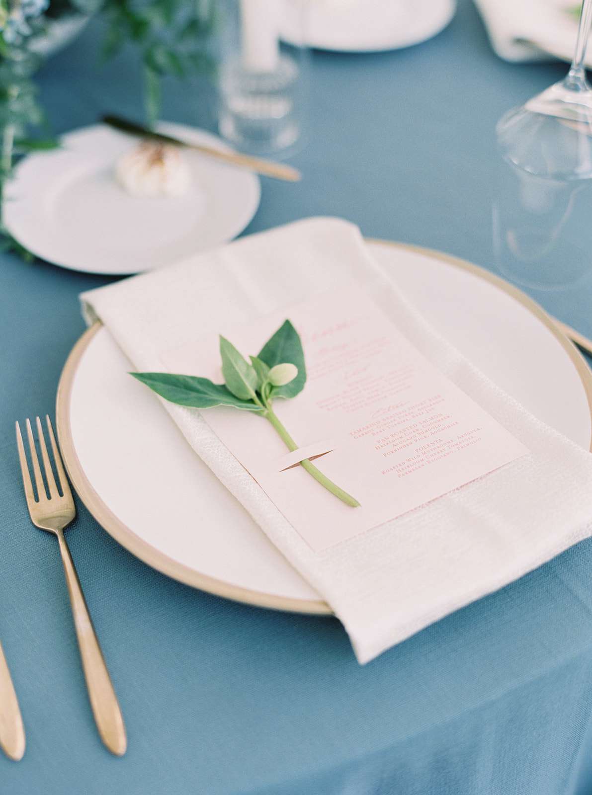 beige toned wedding reception place settings on blue table cloth