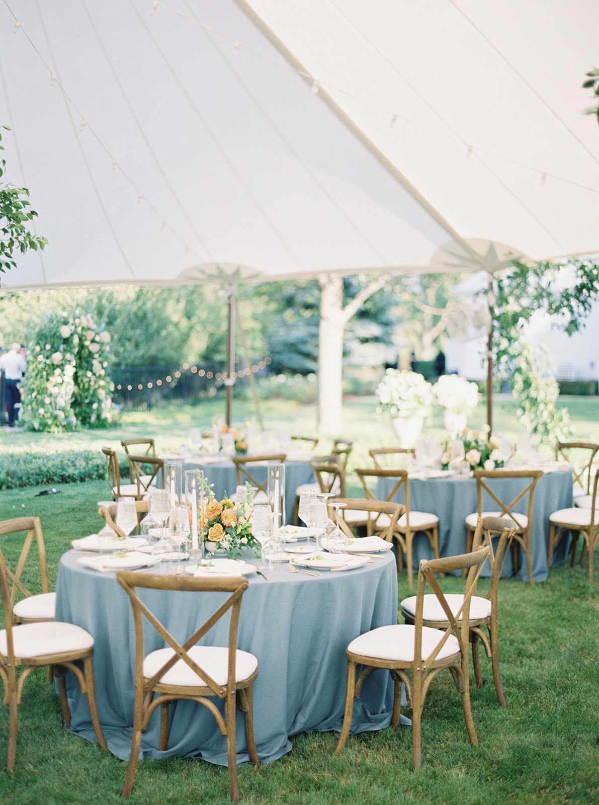 blue linen covered round reception tables under white tent