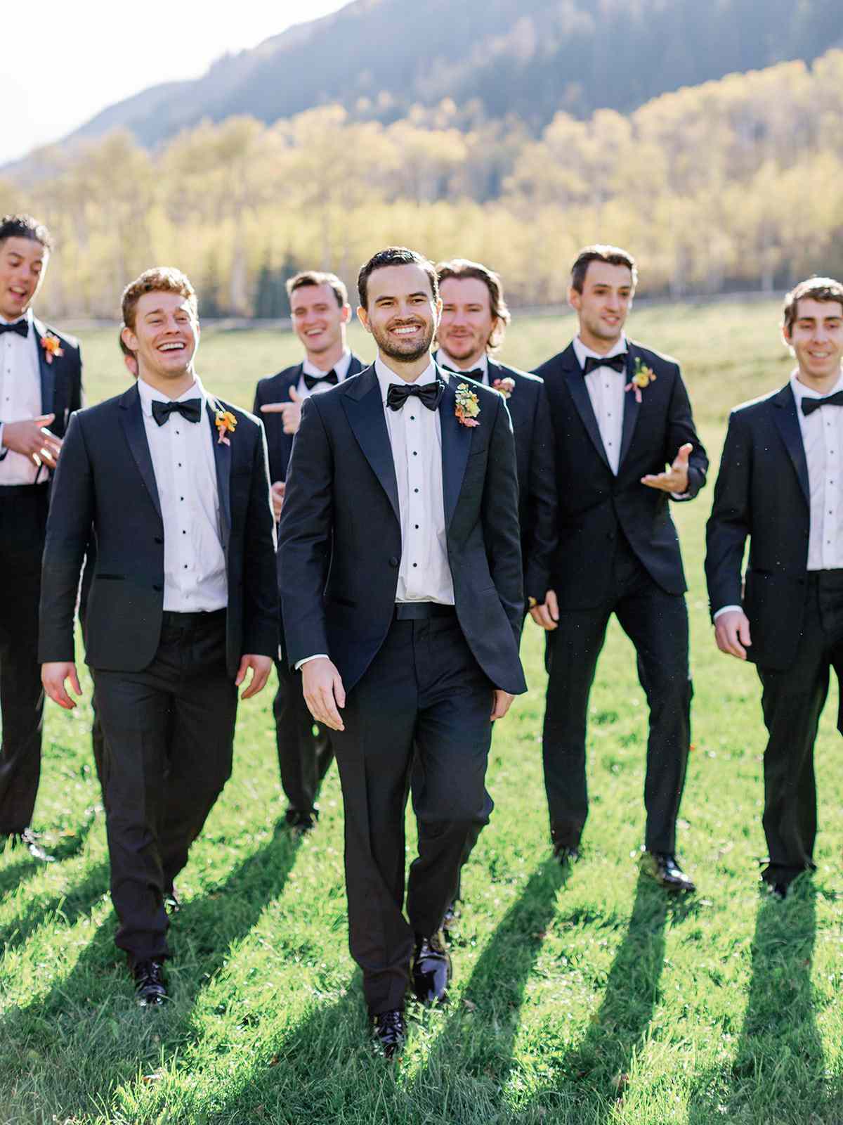 groomsmen in matching navy tuxes with colorful boutonnieres