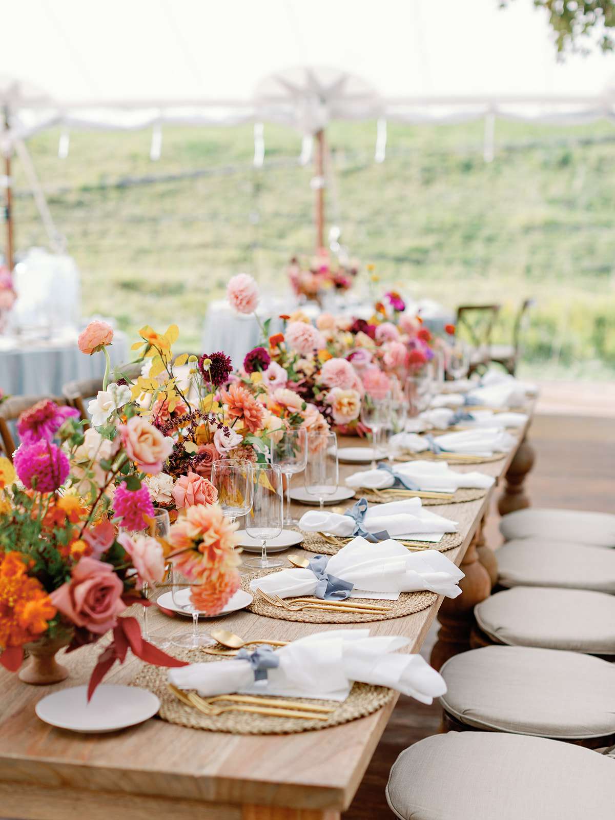 outdoor reception table with colorful floral display with gold accents