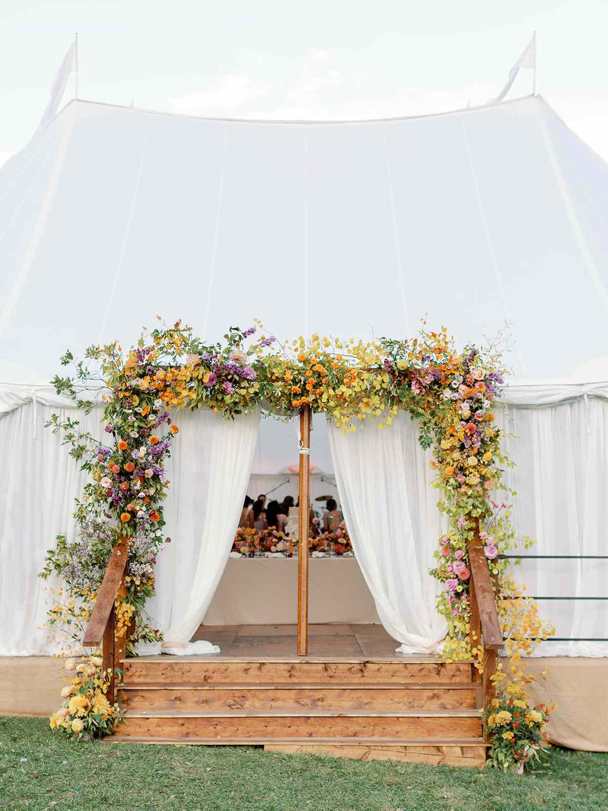 large outdoor reception tent with colorful flowers at the entrance