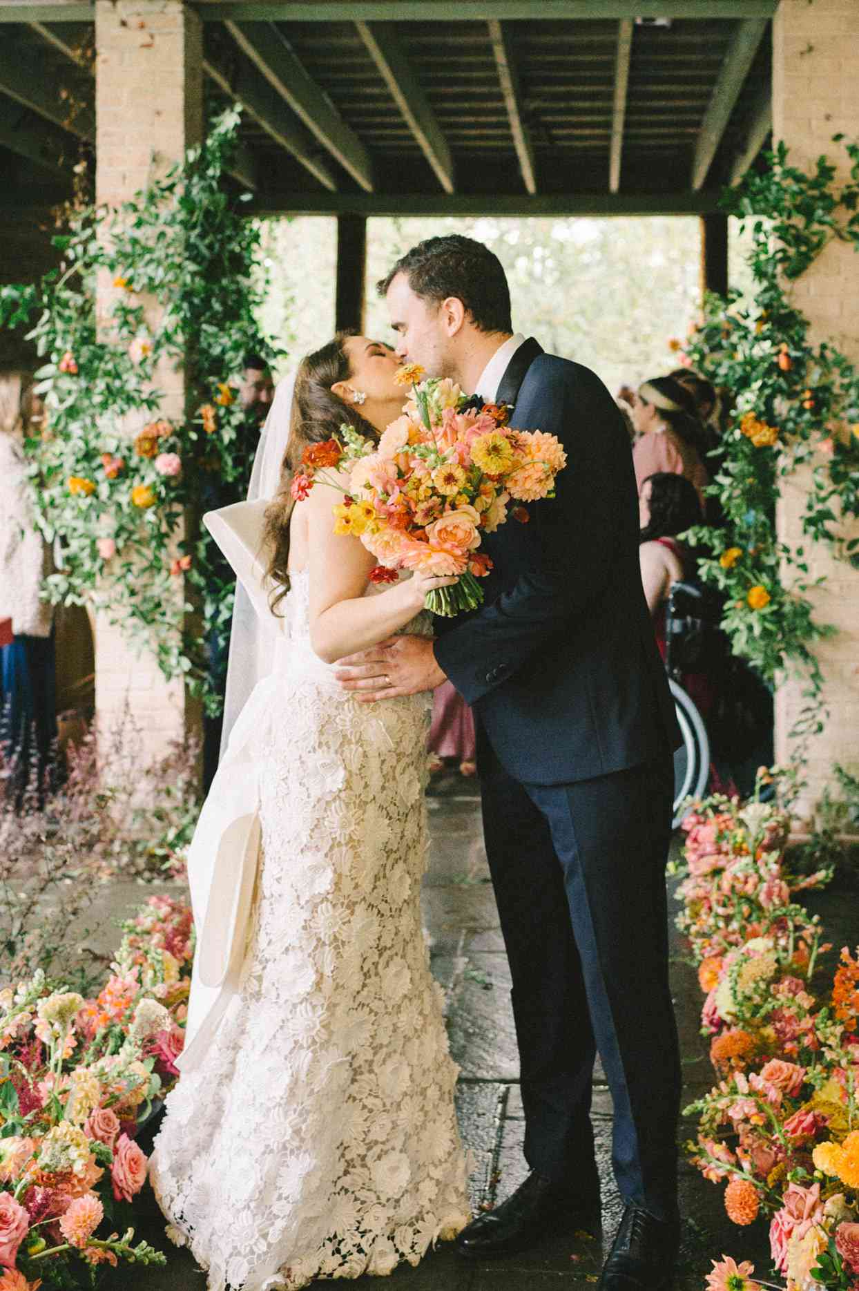 bride and groom share a kiss surrounded by floral arrangements