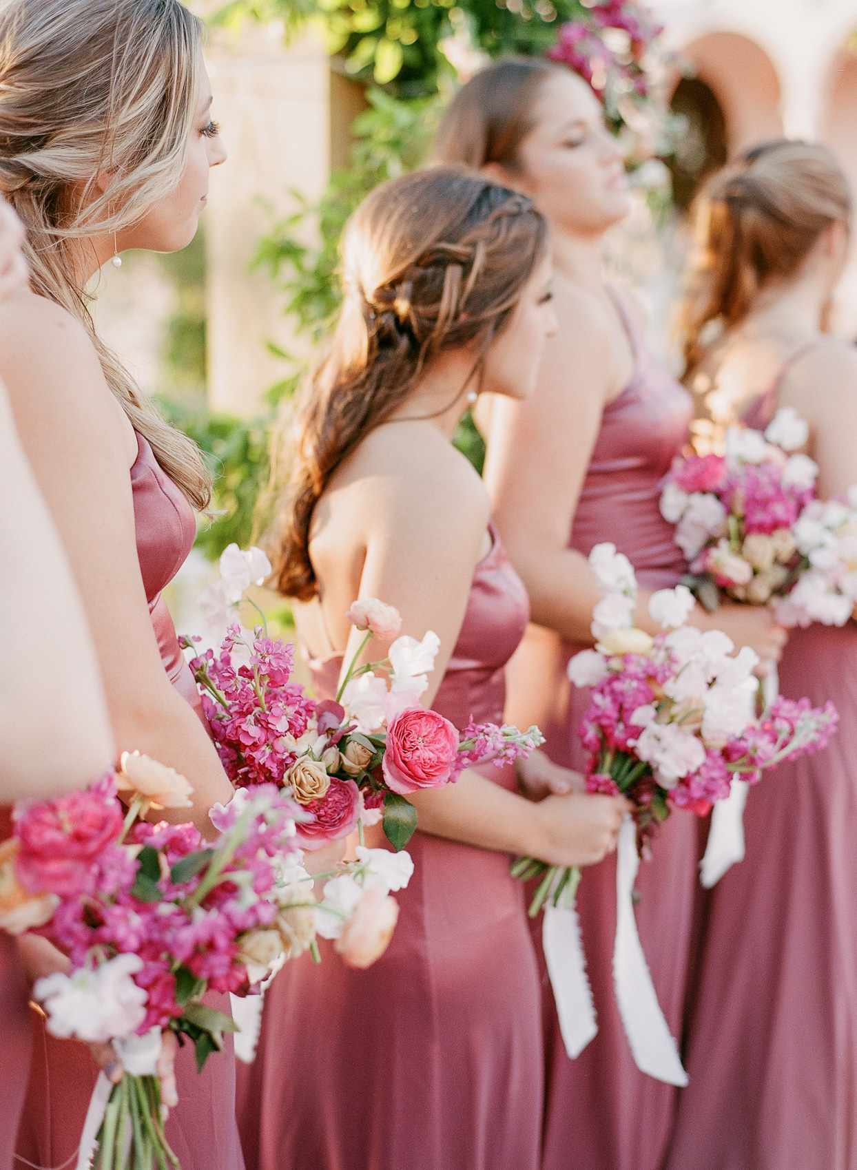 bridesmaids wearing pink dresses holding pink floral bouquets