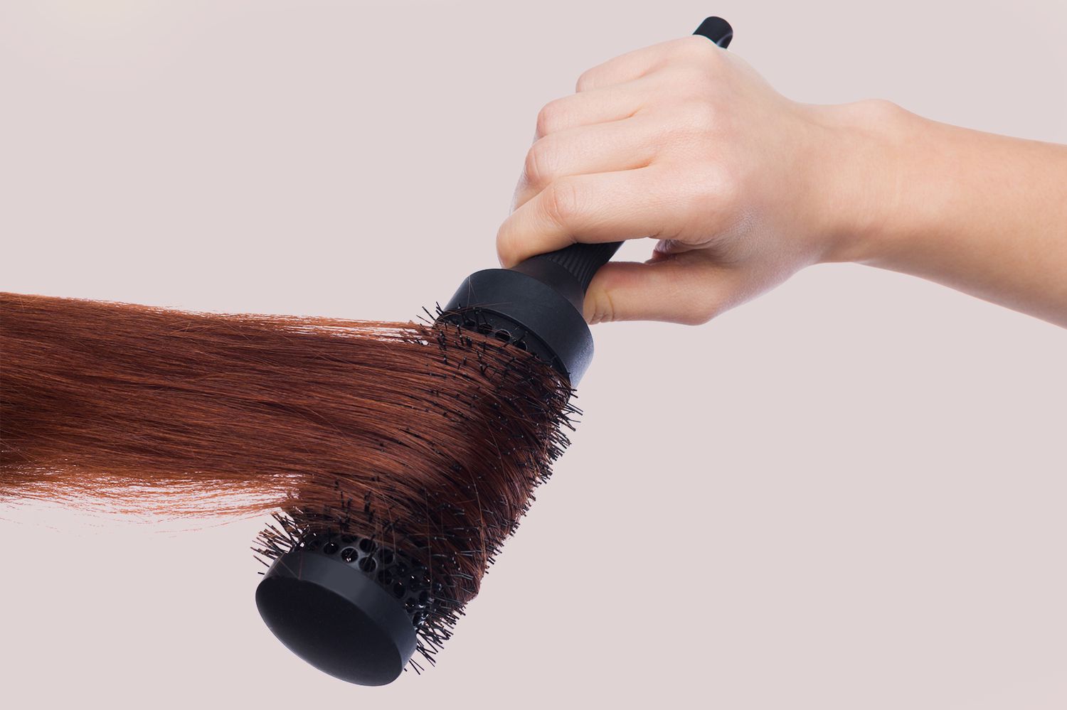 woman using round brush on hair