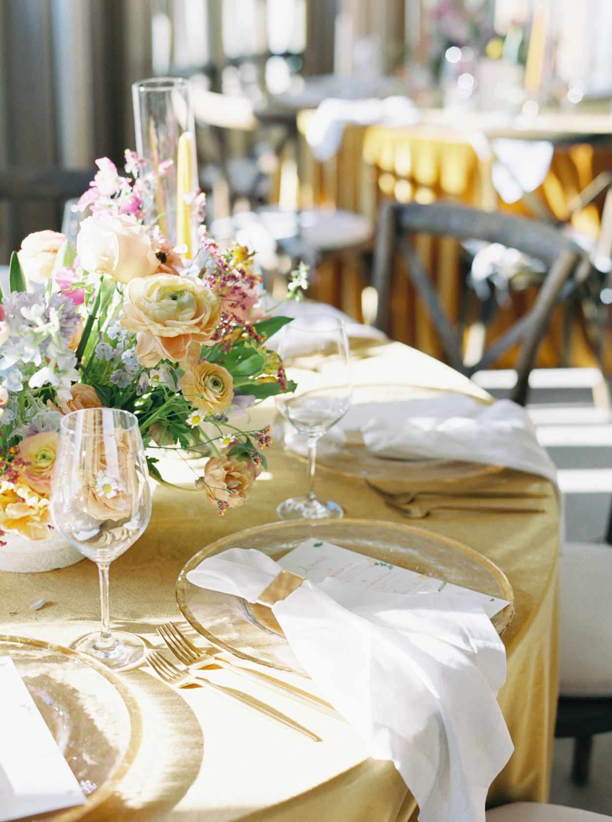 wedding reception place setting with gold flatware and beaded-edge chargers