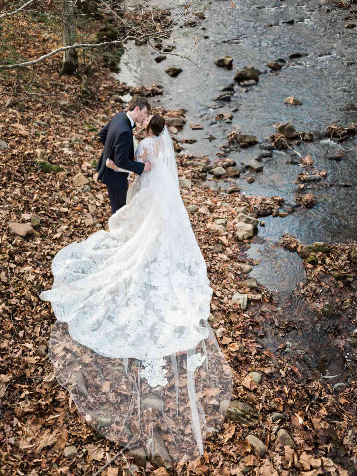 bride and groom kissing next to river bank