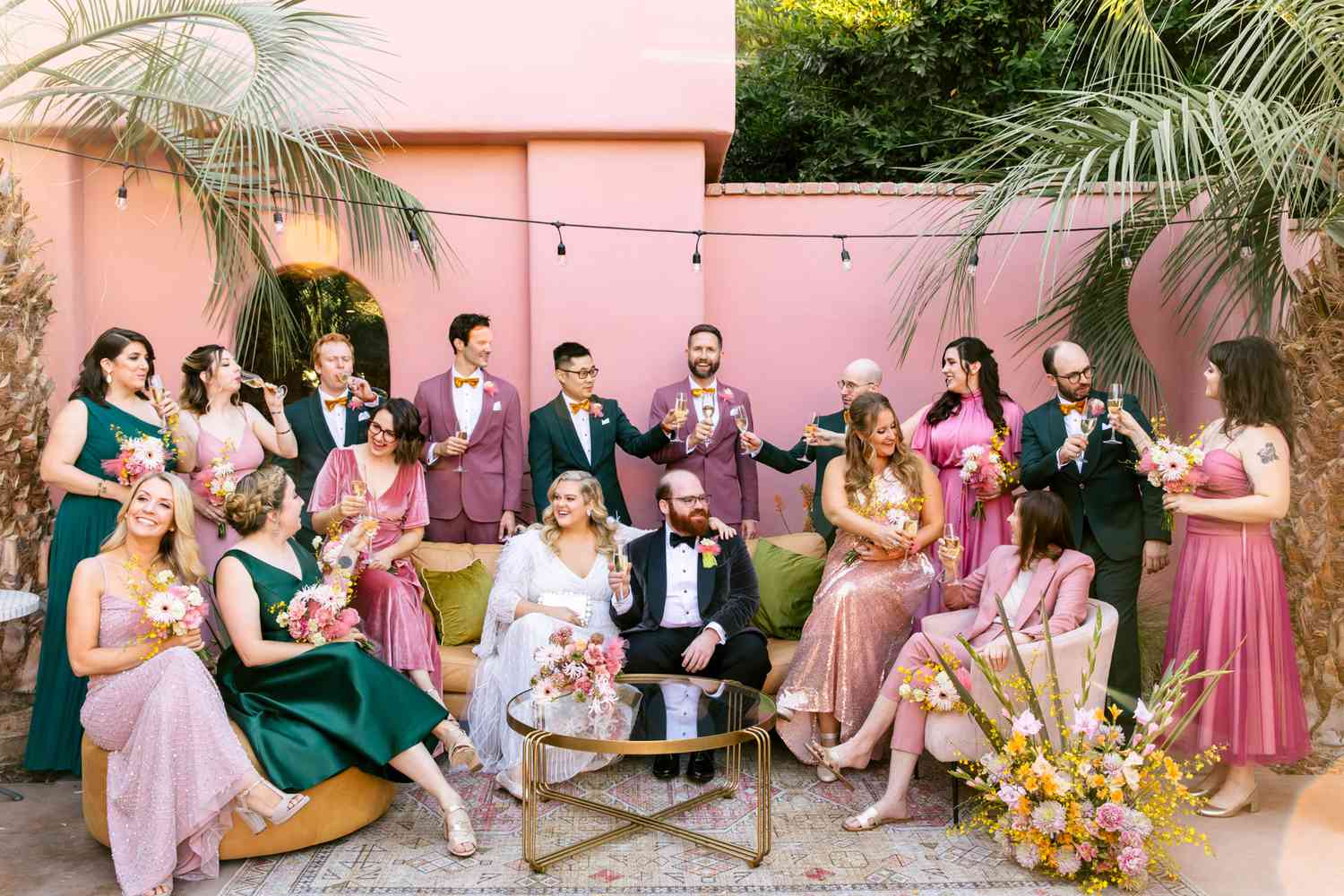 bride and groom with wedding party wearing emerald green and pink toned suits and dresses
