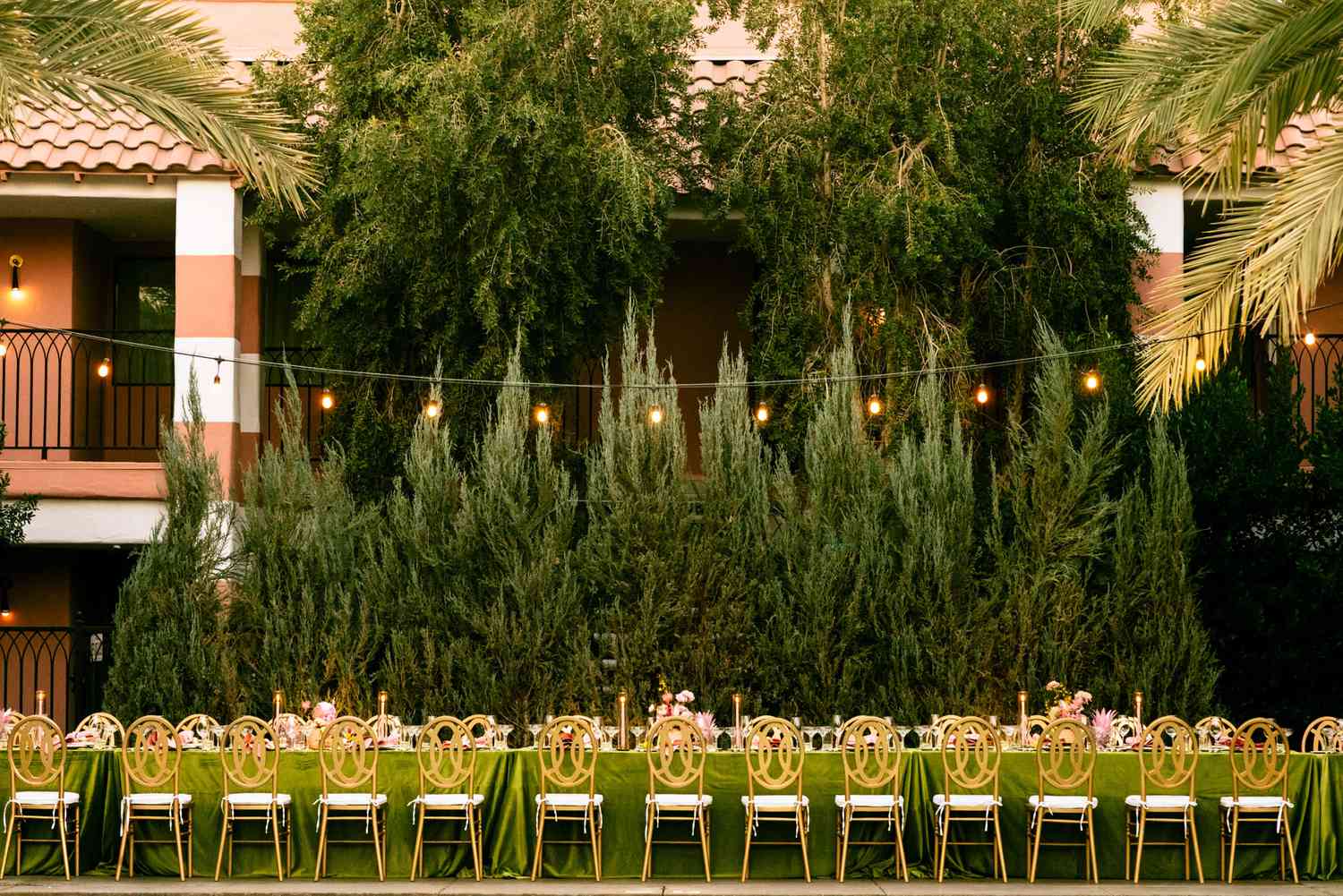long reception table with green tablecloth and gold chairs