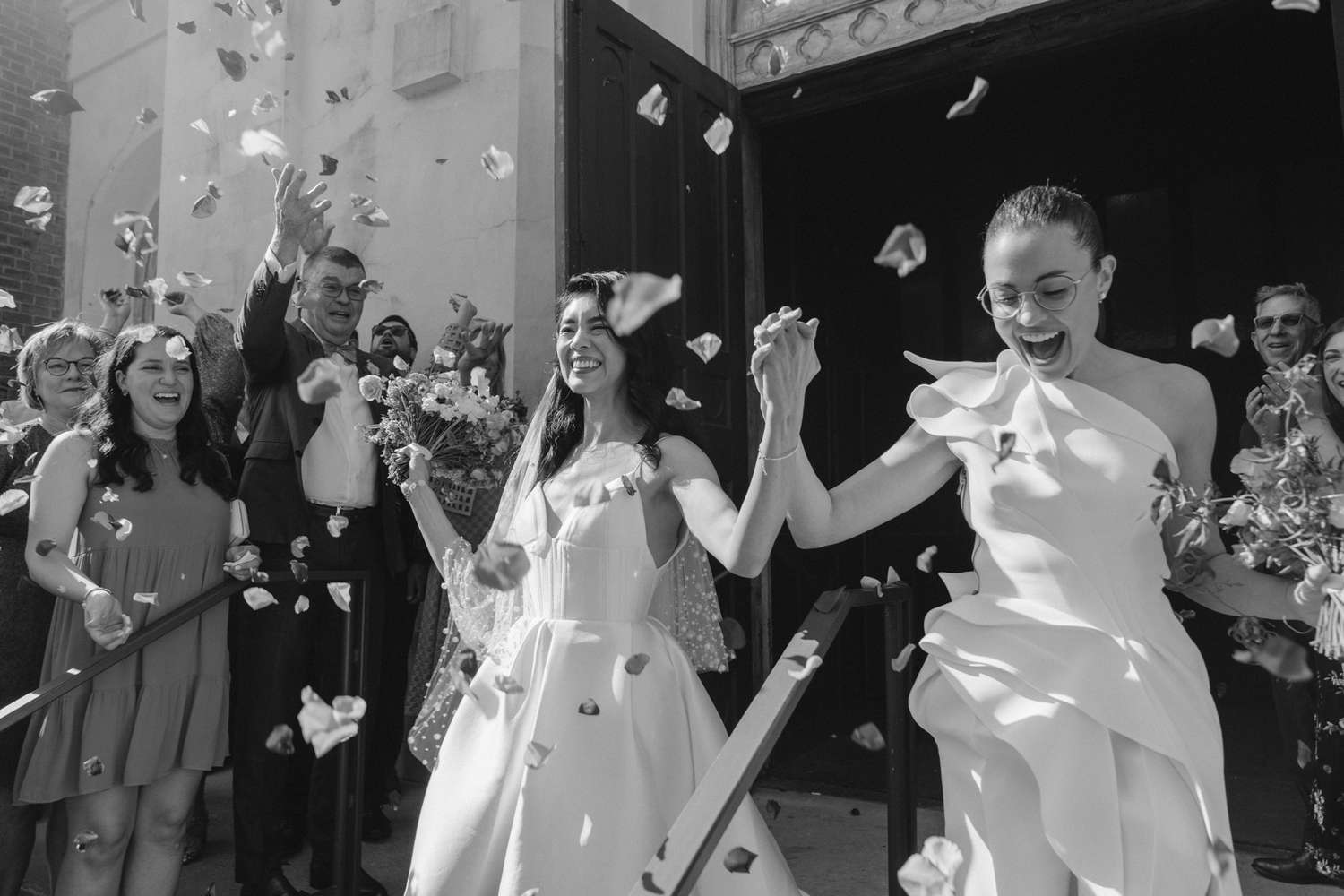 brides exiting the ceremony venue as guests toss flower petals