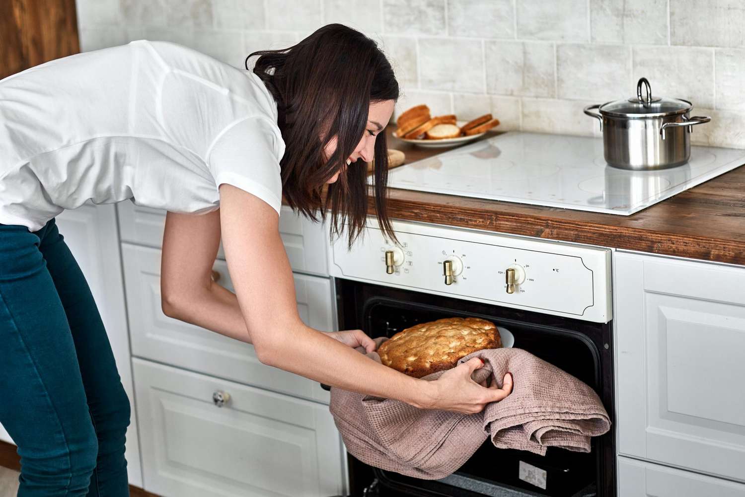 woman taking homemade cake out of oven