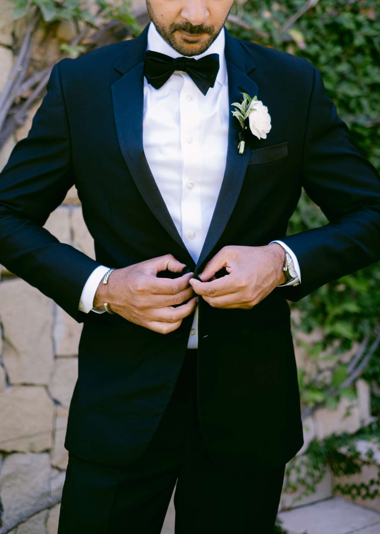 groom buttoning black tuxedo
