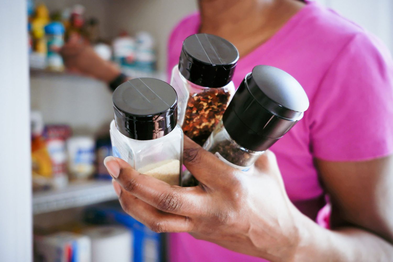 Close-up of unrecognizable black woman grabbing spices from pantry