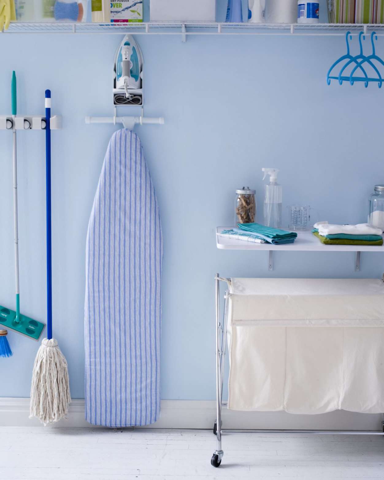 Laundry room with ironing board hanging on wall