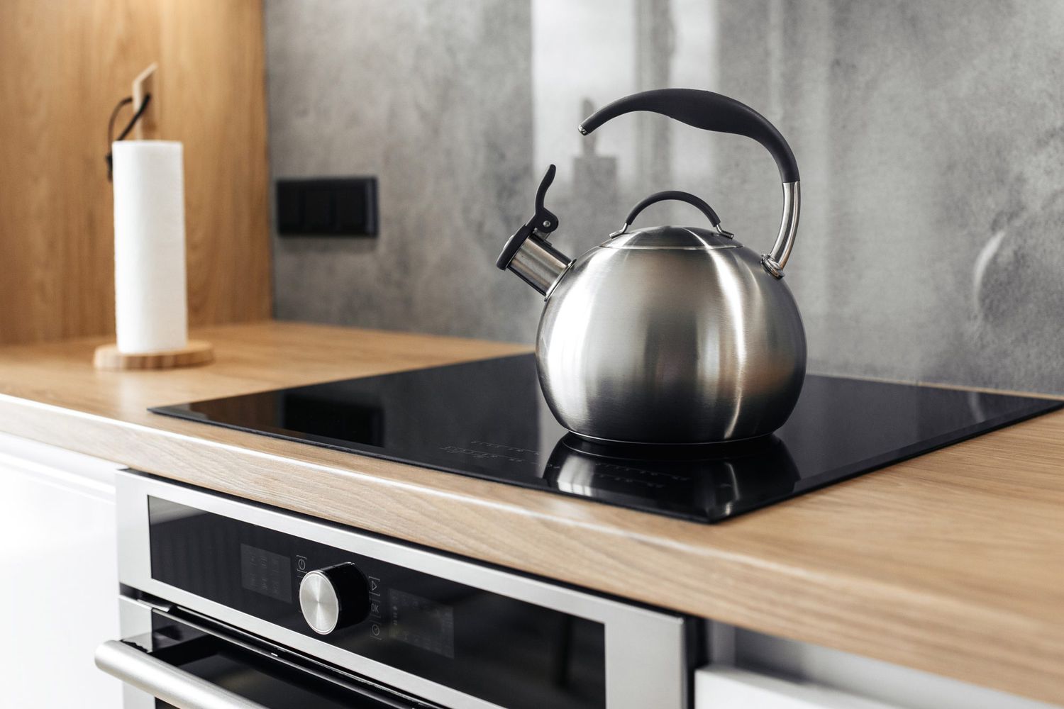 Photo of gray stainless steel kettle on the induction cooktop in the kitchen