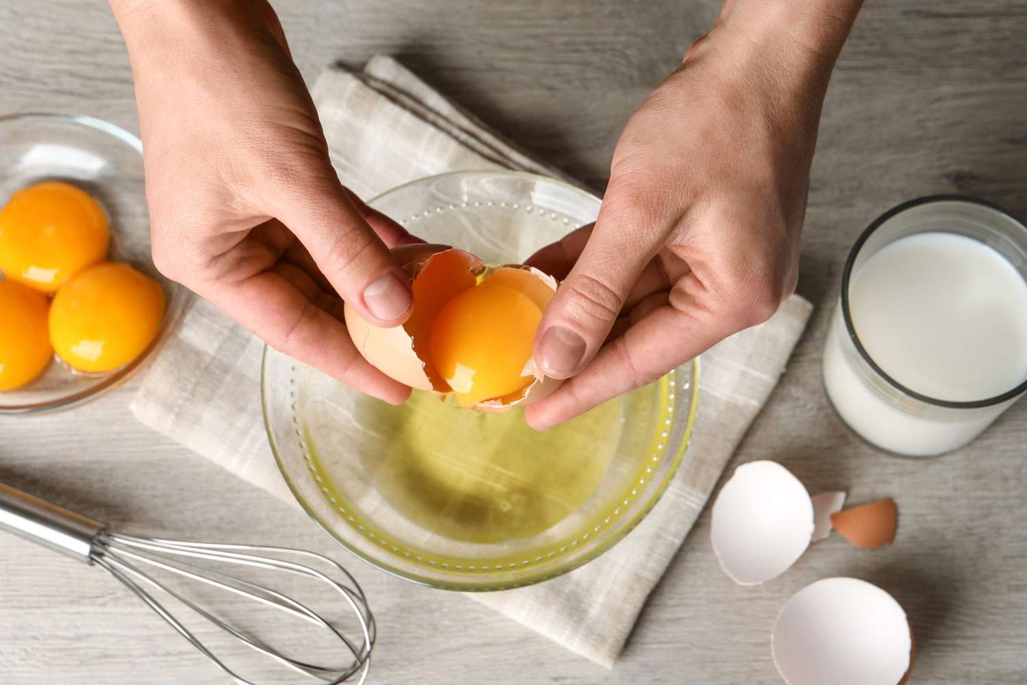 Woman separating egg yolk from white over glass bowl