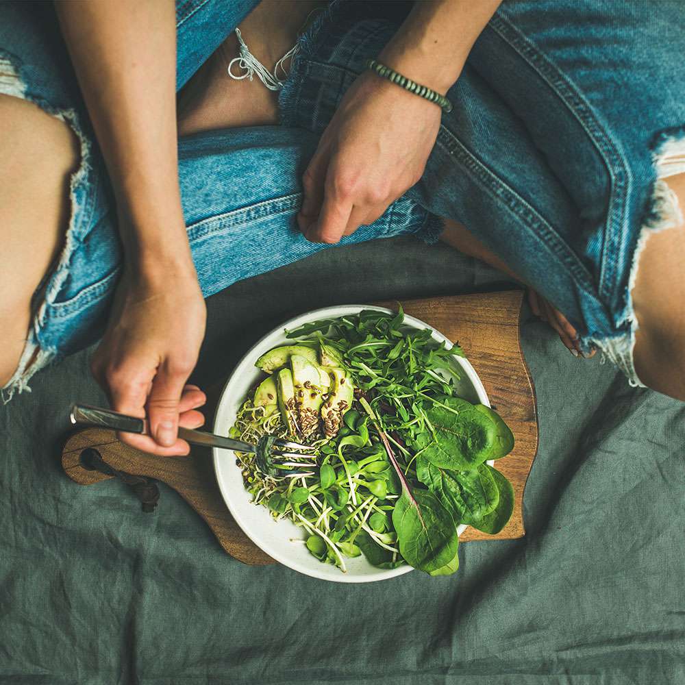 woman eating vegetables as part of a healthy lifestyle habits challenge