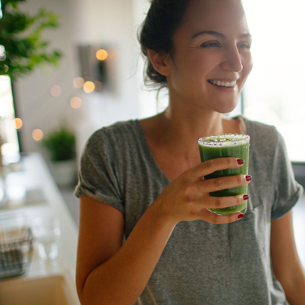 woman drinking green vegetable smoothie